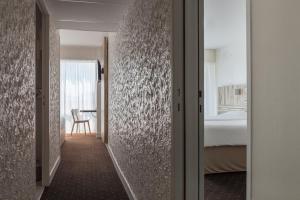 a corridor of a hotel room with a bedroom at Hôtel Le Nautic in Arcachon