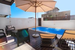 a patio with a tv and an umbrella and a pool at Seasonal Villa in Flic-en-Flac