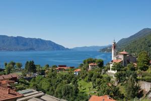 vistas al lago y a una ciudad con un faro en Nido sul Lago Maggiore en Maccagno Superiore