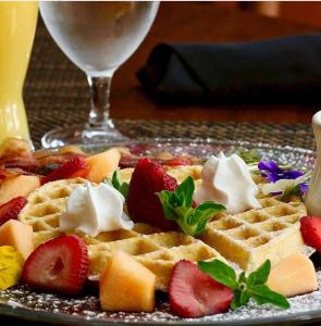 a plate of waffles with strawberries and whipped cream at Highlands Inn in Highlands