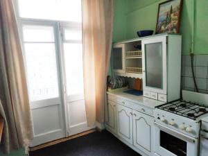 モスクワにあるАпартаменты улица Автозаводскаяの白いキャビネット、コンロ、窓付きのキッチン