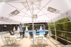 een patio met tafels en stoelen onder een witte parasol bij Hotel Dedal in Mamaia Nord – Năvodari