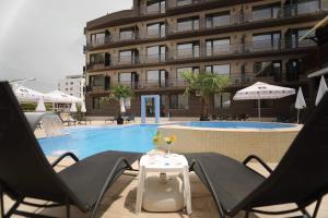 a pool with chairs and a table and a building at Hotel Dedal in Mamaia Sat/Năvodari