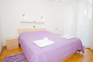 a bedroom with a purple bed with two towels on it at Apartment Zvone in Baška