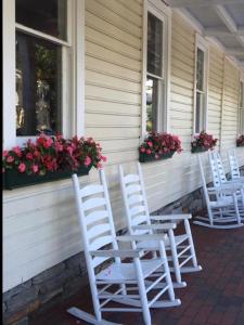 three white rocking chairs sitting on a porch with flowers at Highlands Inn in Highlands