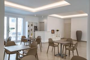 Vasto Aparthotel في فاستو: غرفة طعام مع طاولات وكراسي ومطبخ