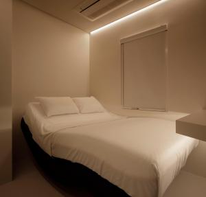 a white bed in a room with a window at hotel min. in Tokyo