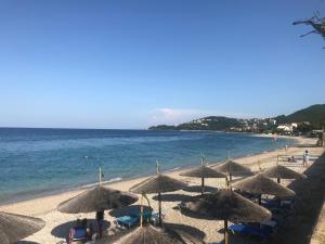 a beach with many straw umbrellas and the ocean at Natalia Studios in Poros