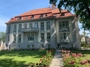 a large house with a red roof and flowers at Hotel Willa Starosty in Międzyrzecz