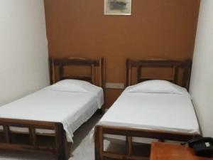 two beds in a room with white sheets at HOTEL NES in Maicao