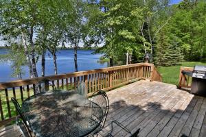 a table and chairs on a deck with a view of the water at Birch Bark Lodge Condo in Hayward