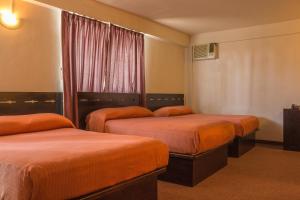 a hotel room with three beds and a window at BONITTO INN® Tampico Altamira in Tampico