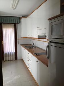 cocina con armarios blancos y nevera de acero inoxidable en Apartamentos Turisticos Puerta de León, en León