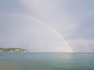 a rainbow over a body of water with a beach at Guest House on Rechnaya 14G in Lidzava