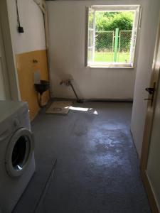 een lege kamer met een wasmachine en een raam bij Ubytování U Trůdy in Smržovka