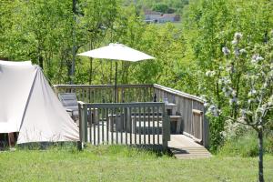 a wooden deck with an umbrella and a tent at Ingerichte tenten Domaine les Gonies in Mauroux