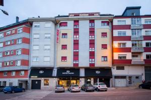 ルーゴにあるU-Hotel Darío Lugoの駐車場に車が駐車されている大きな建物