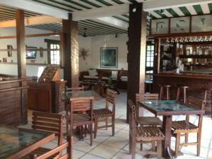 un restaurante con mesas y sillas de madera y un bar en Barla Inn Suites, en Búzios