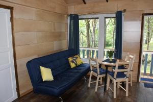 a living room with a blue couch and a table at Kempings Ezerpriedes in Burtnieki