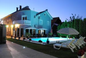a blue house with a swimming pool and chairs and an umbrella at Vila DeLux in Negotin