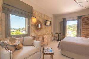 a bedroom with a bed and a couch and a window at Perla Luxury Living in Parga