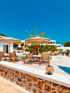 een groep stoelen en parasols naast een zwembad bij Mythos Luxury Villa in Faliraki