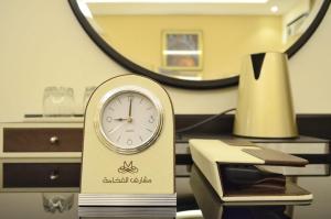 eine Uhr auf einem Schreibtisch vor einem Spiegel in der Unterkunft مشارف الفخامة أبها in Abha