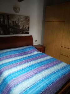 a bed with a colorful striped comforter in a bedroom at Condominio La Rasica in San Martino di Castrozza