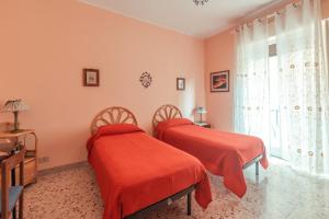 two beds in a room with red sheets and a window at Theokles Apartment in Taormina