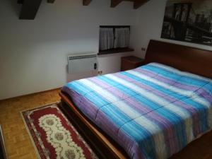 a bedroom with a bed with a colorful blanket at Condominio La Rasica in San Martino di Castrozza