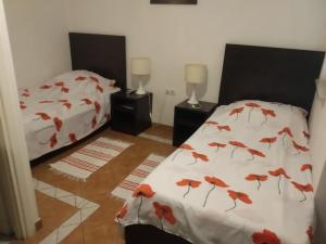 um quarto com duas camas com folhas vermelhas nos lençóis em Rooms Lutra em Bilje
