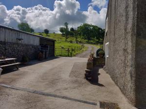 a dirt road next to a building with a gate at Row Farm Cottage in Millom