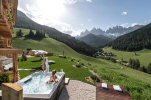 a woman sitting in a bath tub in a mountain at Unterkantiolerhof in Funes