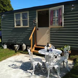 une terrasse avec une table et des chaises devant une maison dans l'établissement The English shepherds hut @ Les Aulnaies, à Échauffour