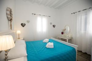 una camera da letto con un letto blu e asciugamani di Venus Myconian Residences a Kalafatis