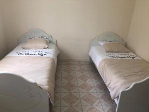 2 Betten in einem kleinen Zimmer mit Fliesenboden in der Unterkunft Villa plein pied rez-de-chaussée+1 avec dépendance in Cenon