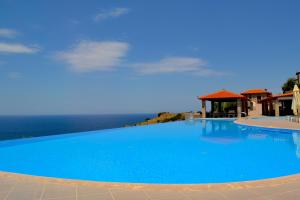 een groot blauw zwembad met de oceaan op de achtergrond bij Villa Molivos Castle in Mithimna