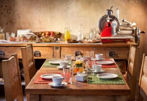 una mesa de madera con platos y vasos. en Posada Borravino en Chacras de Coria