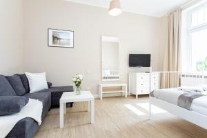 uma sala de estar branca com um sofá e uma cama em Riviera Rooms em Sopot