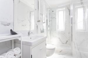 a white bathroom with a sink and a shower at Riviera Rooms in Sopot +12 photos