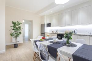 a kitchen and dining room with white cabinets and tables and chairs at Riviera Rooms in Sopot