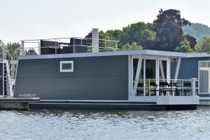 uma casa-barco está ancorada numa doca na água em Cozy floating boatlodge "Maastricht". em Maastricht