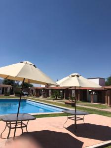 twee tafels en parasols naast een zwembad bij Villas Amalur in Tequisquiapan