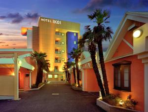 a hotel with palm trees in front of a building at ホテル イコイ in Kawaguchi