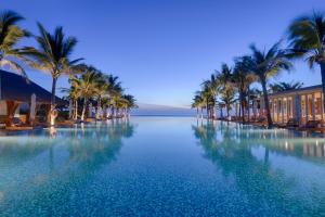 a large pool of water with palm trees and buildings at Naman Retreat in Danang