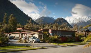 un coche aparcado en un estacionamiento con montañas en el fondo en 58 On Cron Motel, en Franz Josef