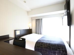a bedroom with a bed and a table and a window at APA Hotel Shimbashi Onarimon in Tokyo
