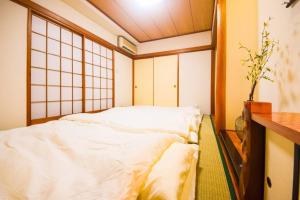 um quarto com uma cama branca num quarto em Ryokan -Ryo- em Tóquio