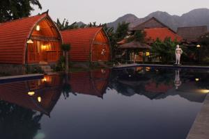 a person standing next to a swimming pool in a resort at Kubu Padi Wooden House in Pemuteran