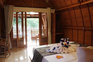 a bedroom with a bed with two swans on it at Kubu Padi Wooden House in Pemuteran